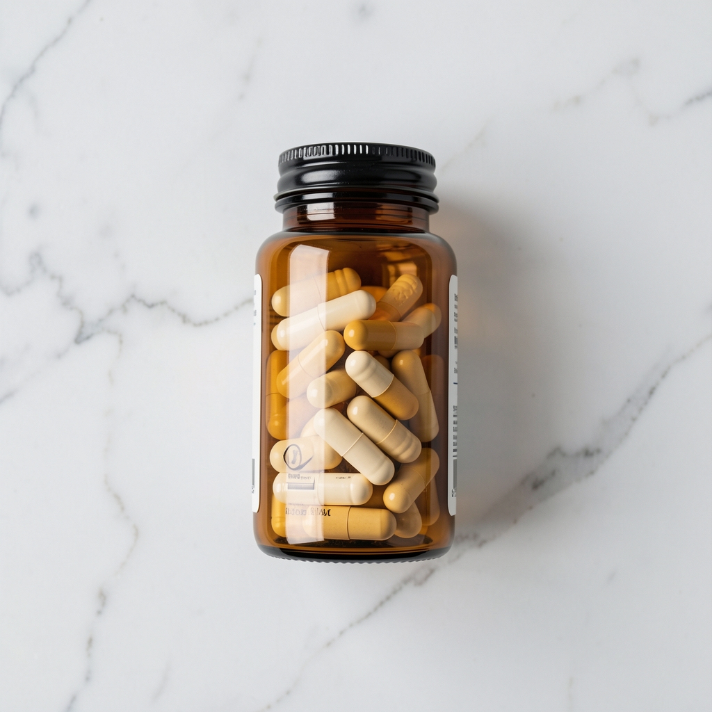Daily supplement capsule bottle in amber glass, placed on a white marble surface, editorial overhead perspective, clean background